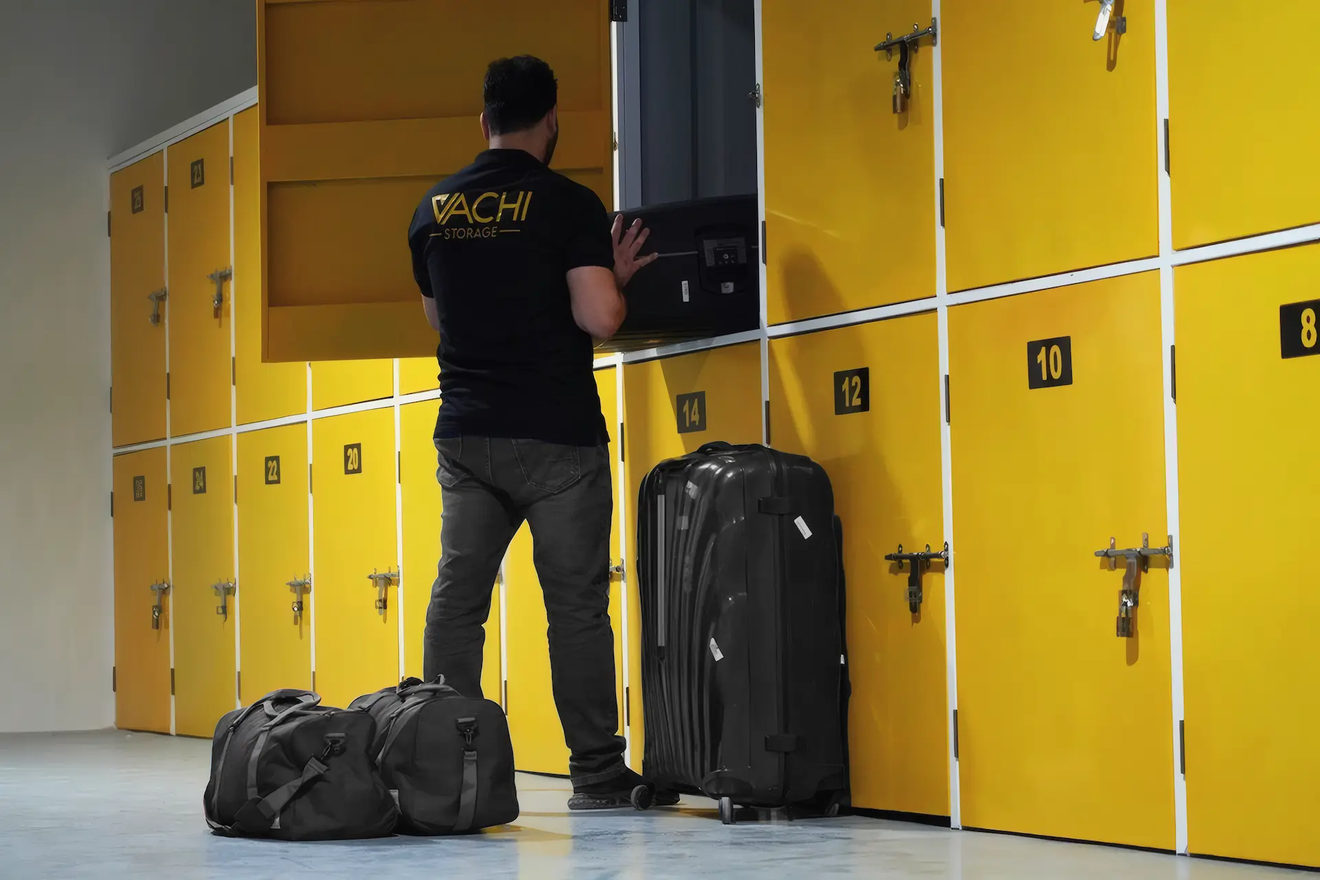 A Vachi team member loading a yellow half-height locker, with luggage beside him